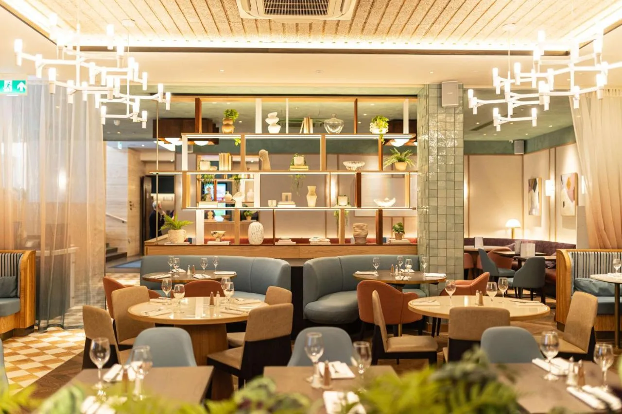a restaurant with tables and chairs and chandeliers at DoubleTree by Hilton London Victoria in London