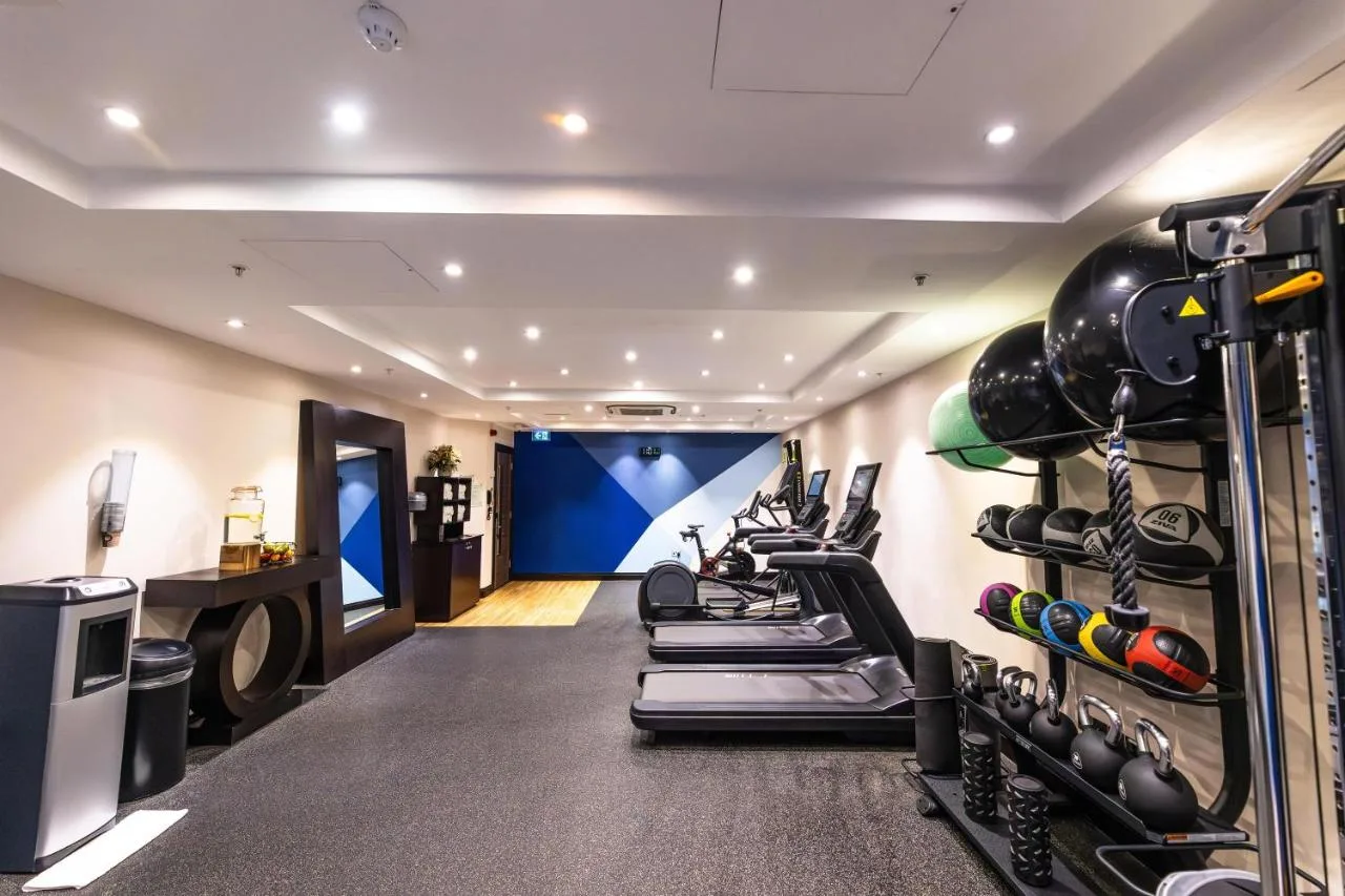 a gym with a row of treadmills and weights at DoubleTree by Hilton London Victoria in London